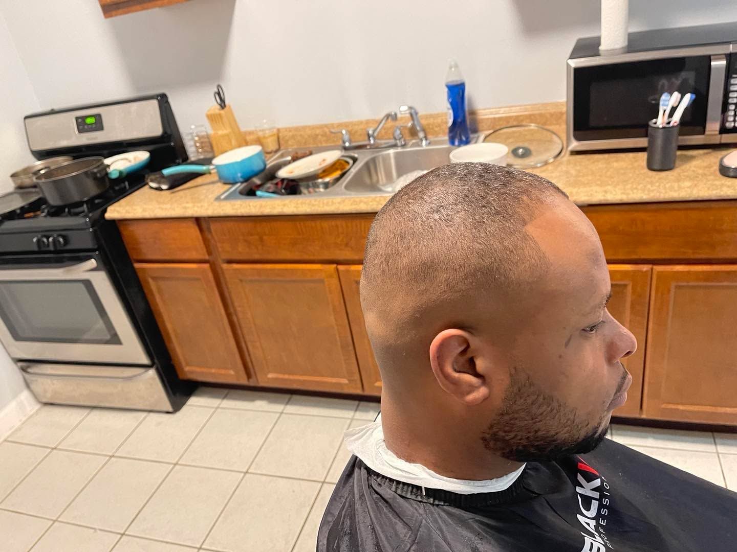 Side profile of a low fade with an even short top and a lined beard